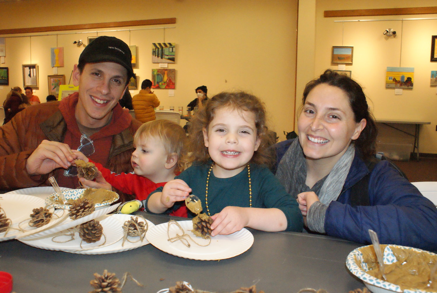 BIRD FEEDERS: The Durante family, Devan, Miles age 1, Marcella age 3 and Lauren, makes bird feeders out of pine cones, peanut butter and bird seed at Winterfest at the Central Library.